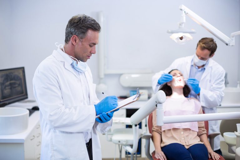 Dentista escribiendo notas en un portapapeles en la consulta dental