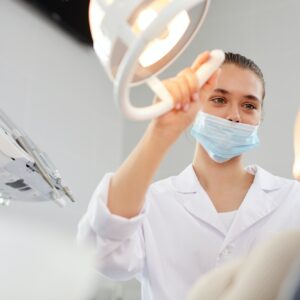 Female dentist adjusting lamp