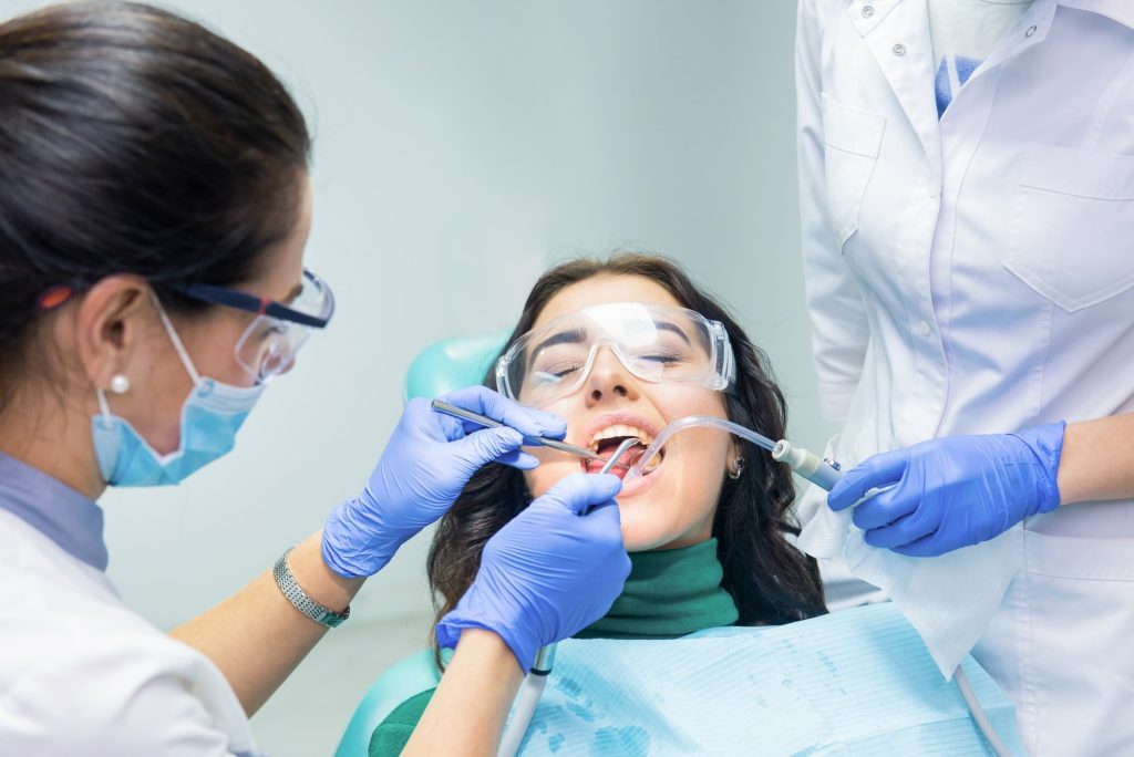 Dos dentistas atendiendo a un paciente en la clínica dental