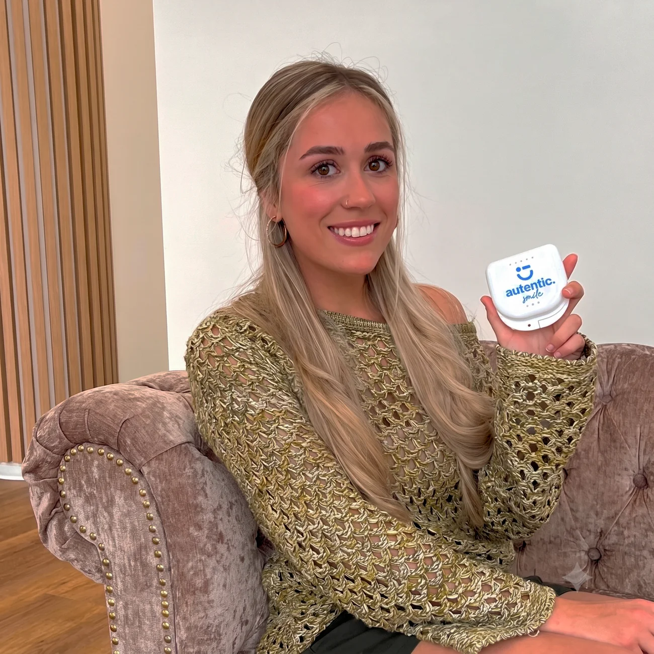 Chica joven rubia sonriente mostrando el estuche de Autentic Smile