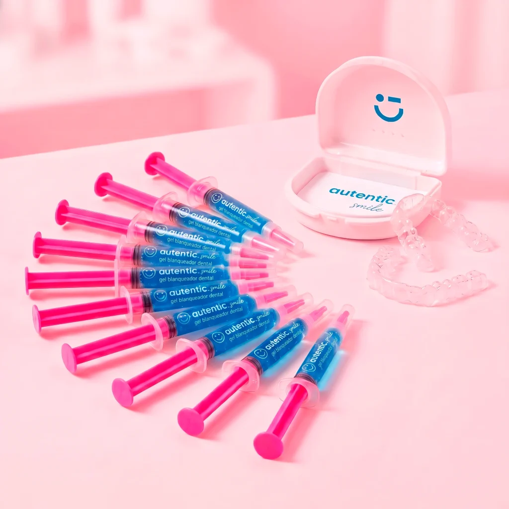 Kit de 10 jeringas de gel blanqueador dental Autentic Smile, con el estuche abierto y la férula transparente sobre fondo rosa