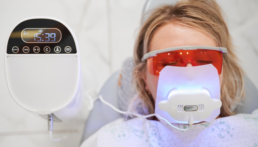 Sesión de blanqueamiento dental con lámpara de luz en una clínica, con gafas de protección